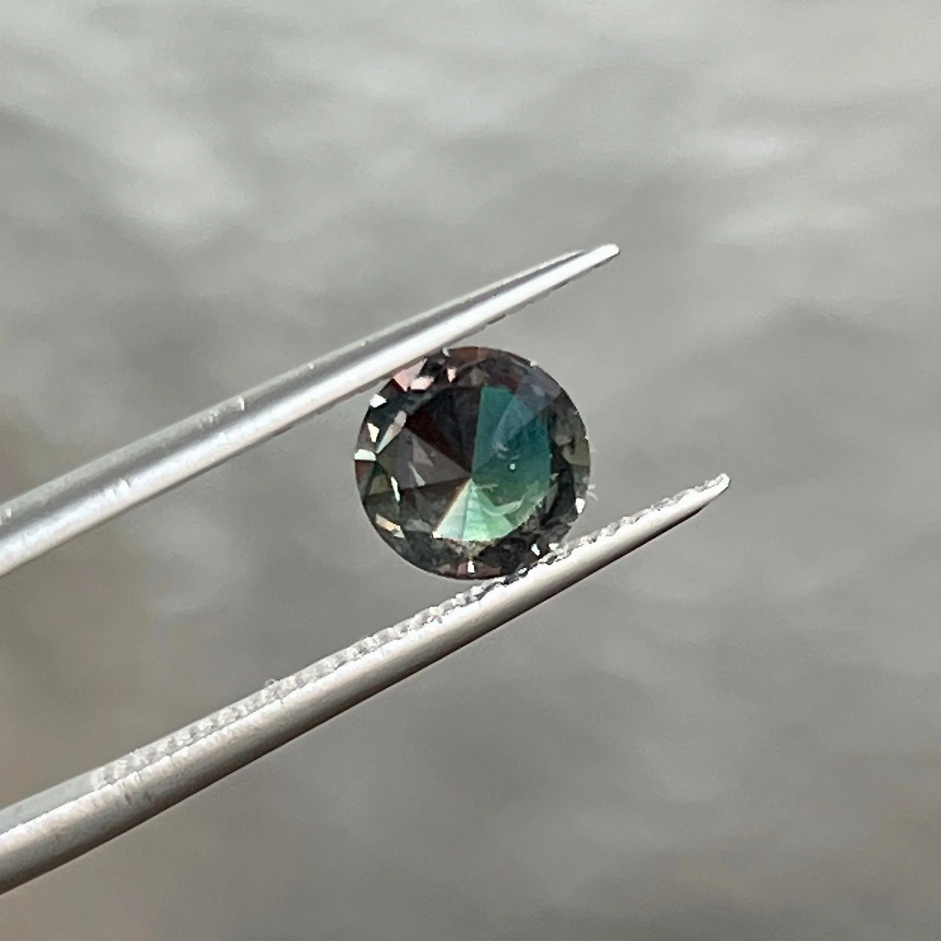 1.17CT BRILLIANT ROUND MADAGASCAR SAPPHIRE, COLOR SHIFTING TEAL TO PURPLE RED WITH OLIVE GREEN FLASHES, 6.65X3.70MM